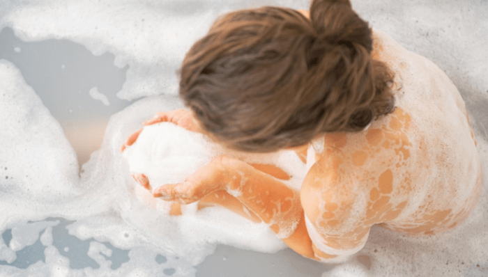 Woman in bathtub with foaming body wash